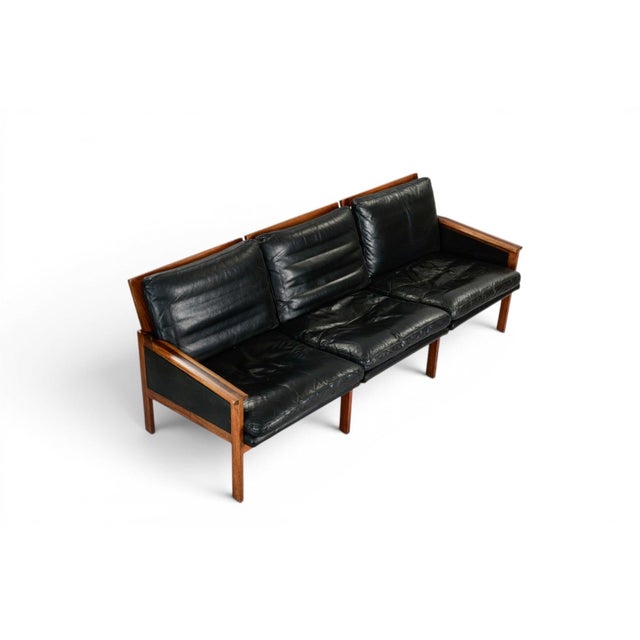 The Capella three-seat sofa, designed by Illum Wikkelsø for N. Eilersen, Denmark, 1950s-60s. A sculptural rosewood frame...