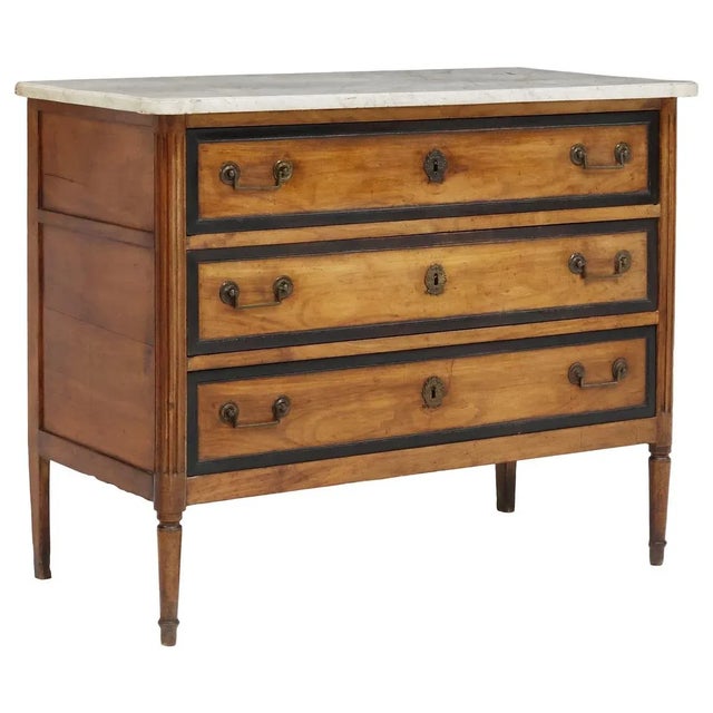 French Louis XVI style fruitwood commode, late 19th c., having shaped marble top, over three drawers with parcel-ebonized...