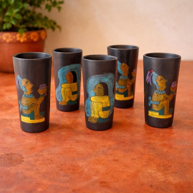 These vintage Arte Levantino Mexican black clay cocktail tumblers feature hand-painted indigenous-style figures in two...