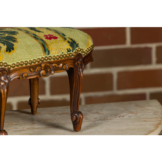 A French Louis XV style carved walnut footstool from the 19th century with tapestry upholstery. This French Louis XV-style...