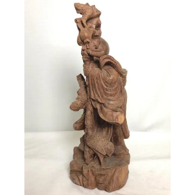 This Asian carved wooden figure of a scholar has tons of charm and character. The scholar is holding a wooden shaft and a...