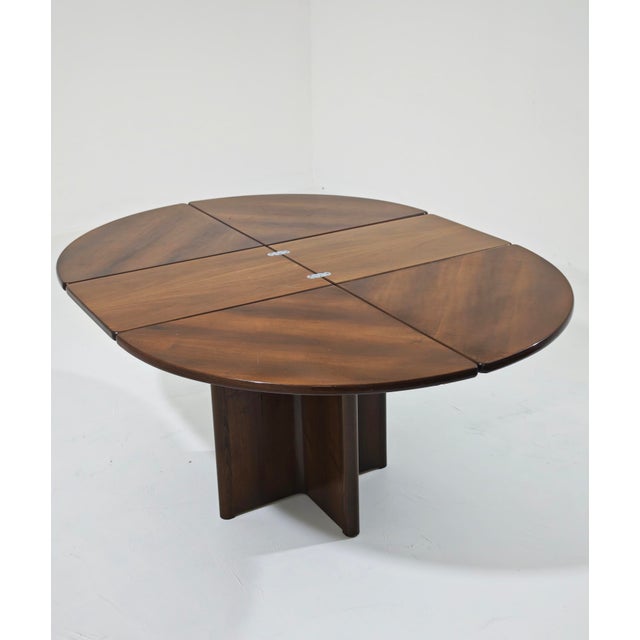 A refined round wooden dining table, reminiscent of the Artona line designed by Afra and Tobia Scarpa for Maxalto or...