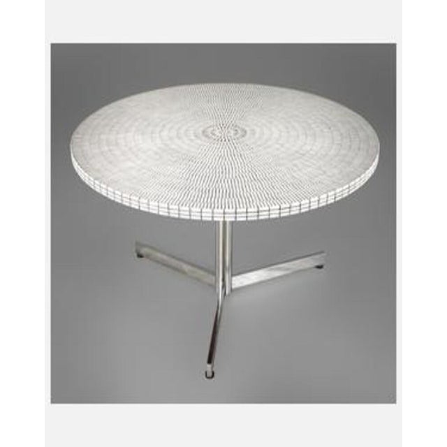Round coffee table with a mosaic-inlaid top featuring small white marble tiles arranged in a radial pattern. Three-...