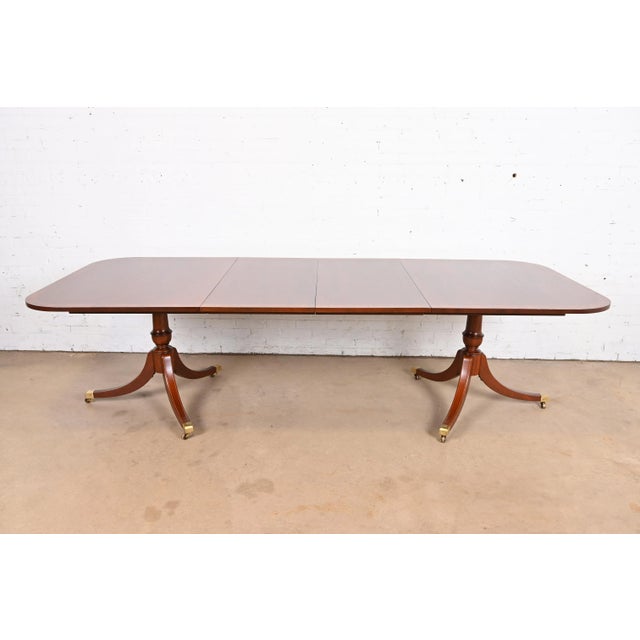 An exceptional Georgian or Regency style double pedestal extension dining table In the manner of Baker Furniture USA,...