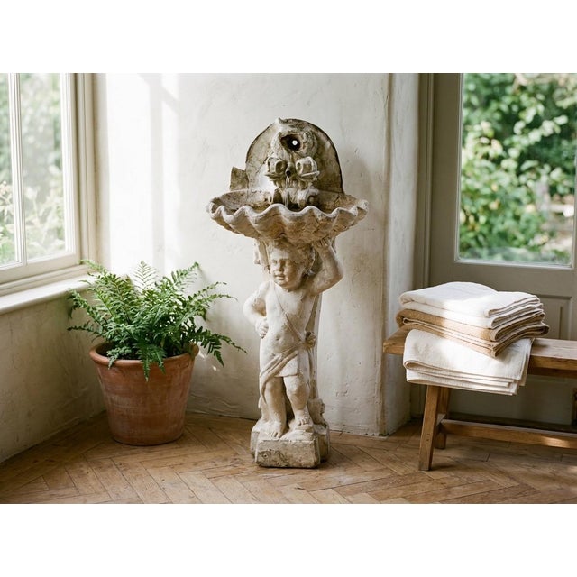 A 19th century French Neoclassical style cast stone fountain. Shell shaped basin with a pair of dolphin spouts is held...