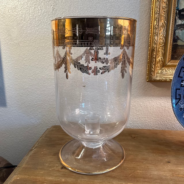 Hand blown large can holder. Elegant gold work along the rim. This Hurricane cancel vase is 13”tall x 7” wide at the...