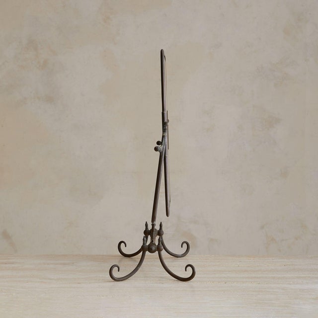 A French table mirror, dating to the 1950s. The rectangular plate tilts within a frame of scrolling metal, raised on four...