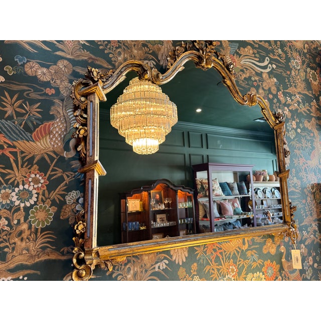 Ornate wall mirror with a lavish gold frame in the Rococo style, which was popular in the 18th century, particularly...
