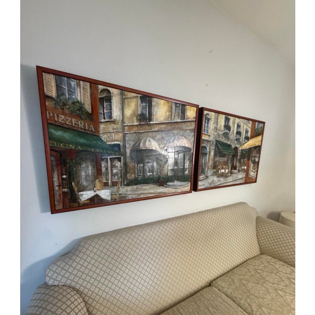 Elegant matching pair of framed European café scene artworks featuring richly layered architectural detail, warm neutral...