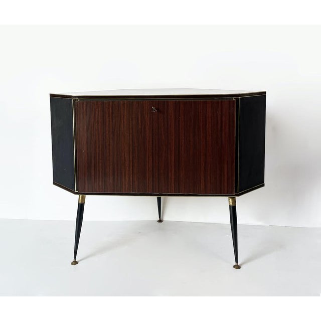 An elegant 1950s bar cabinet made of wood and formica on the outside. Inside, it features a unique rotating storage...