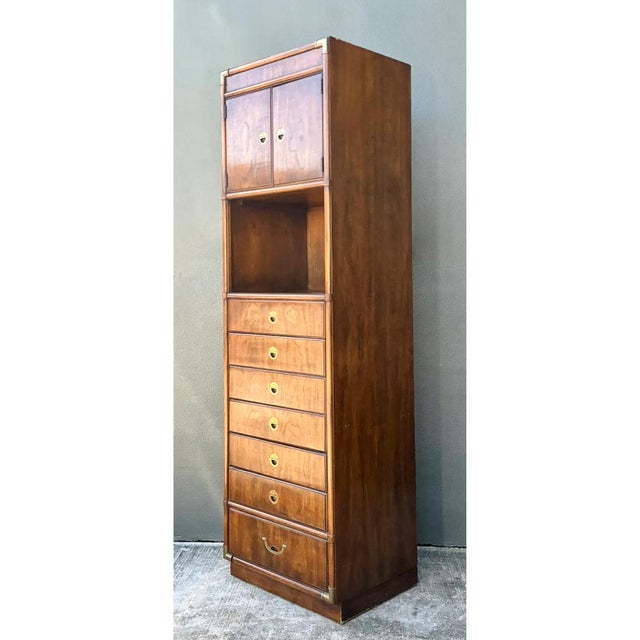 This vintage Drexel campaign tall cabinet is a striking example of mid-20th-century case furniture, distinguished by its...