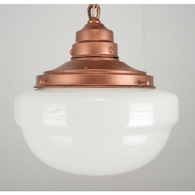 Antique Schoolhouse style pendant light with an antique milk glass globe paired with a newly made copper finish brass...