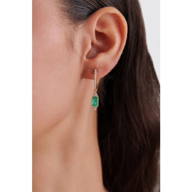 These drop earrings feature a striking 1.96 ct emerald & diamond, set in 14K yellow gold. Each measure is 7 × 5 mm,...