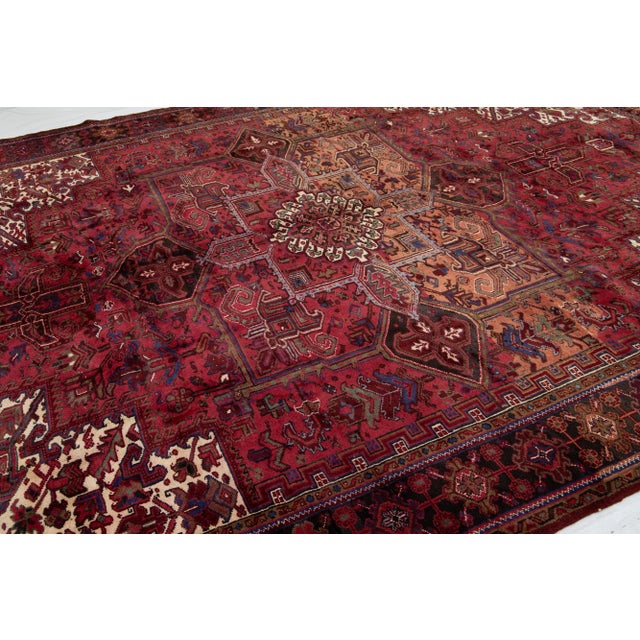 This beautiful Vintage Persian Heriz Wool Rug features a striking red field adorned with an array of beige, blue, and...