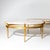 Two oval coffee tables crafted from gold-patinated metal featuring travertine tabletops. These tables are supported by...