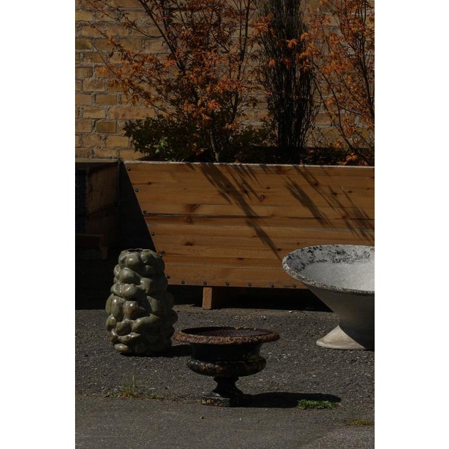 A small antique garden planter in cast iron, featuring a classic rounded bowl form raised on a decorative base. The piece...