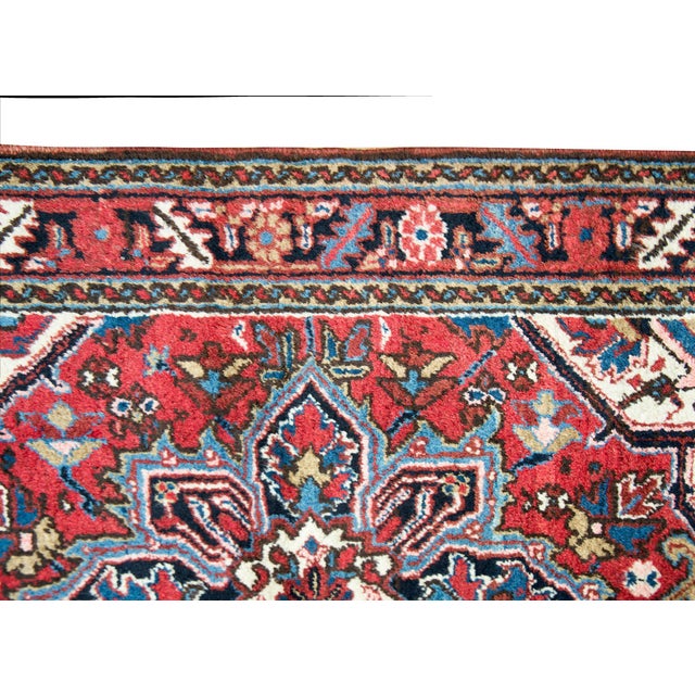 A beautiful early 20th century Persian Heriz rug with a traditional large central floral medallion living amidst a field...