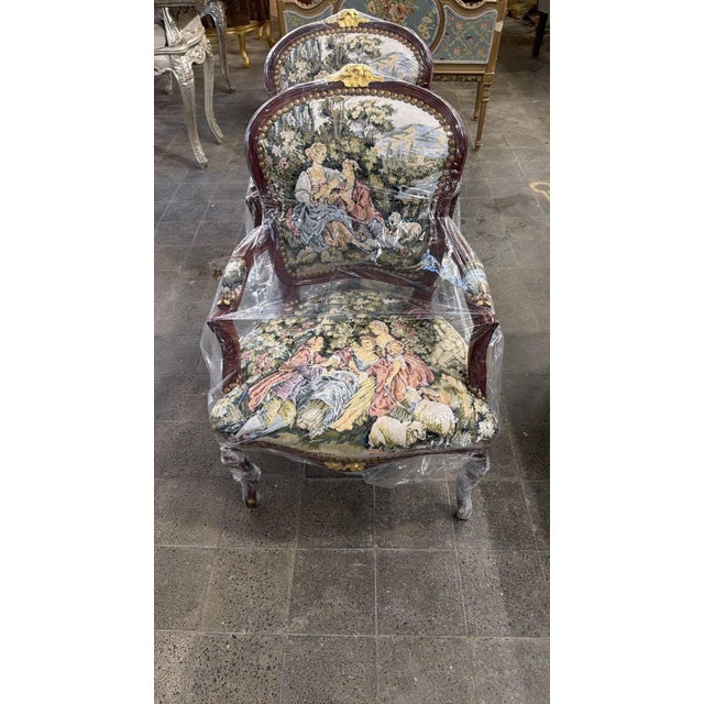 An elegant French Louis XV-style armchairs, beautifully combining an ornate gold-finished carved wood frame with...