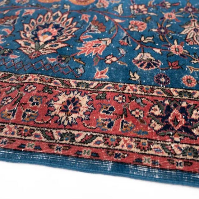 A deep peacock-blue field carrying an allover floral drawn in the Persian Tabriz manner: a pair of saffron-and-coral saz...