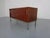 A small, rosewood-veneered sideboard from the 1960s, likely made in Germany. It features two sliding doors, each...