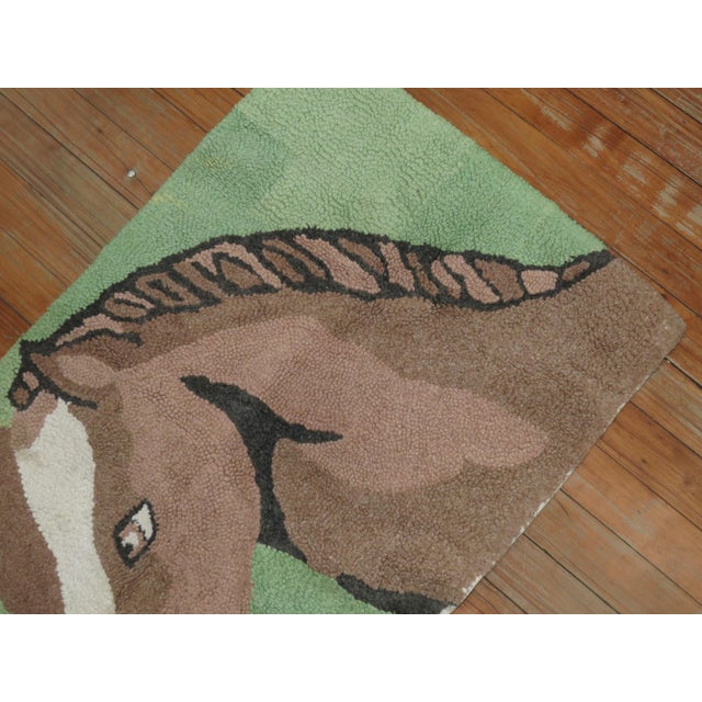 A handmade American hooked rug from the middle part of the 20th century depicting a horse on a mint green background....