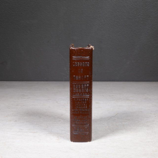 ABOUT Antique "Book of Thrift" featuring a genuine brown leather cover wrapped over a solid metal frame core with brass...