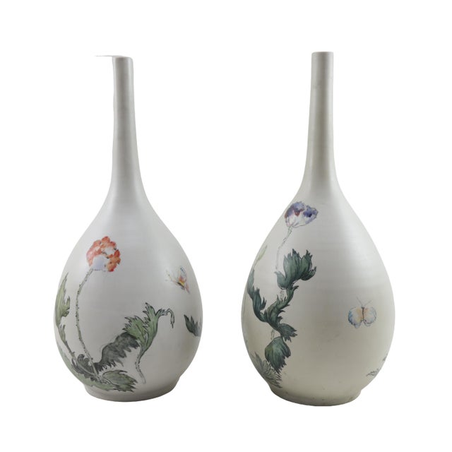 This delicately fluted flask vase has an eggshell sheen that supports the hand-painted flora design as if nurturing the...
