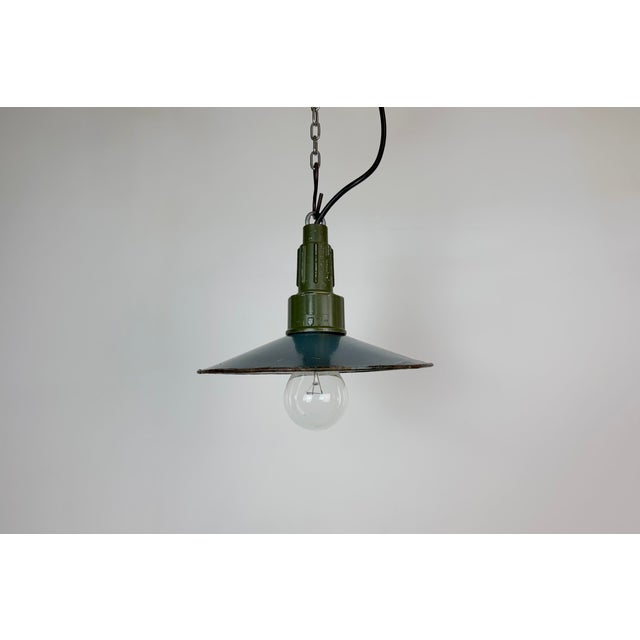 Industrial blue enamel pendant light made in Poland during the 1960s. White enamel inside the shade. Green cast aluminium...