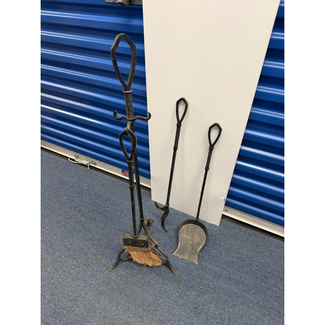 This vintage wrought iron fireplace tool set includes a sculptural scroll‑base stand, shovel, poker, and natural‑fiber...