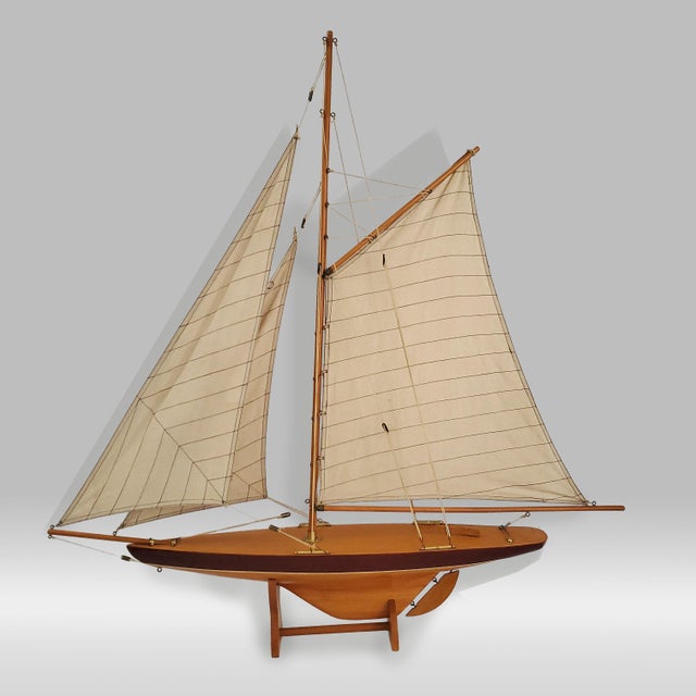 Offering a vintage pond yacht sailboat replica of a 1895 " Defender Cup Racer", circa Late 20th Century. It represents a...
