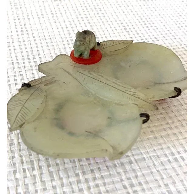 An antique jade carved dish to resemble two peaches. A jade elephant on a carnelian base rests on top of the dish. The...