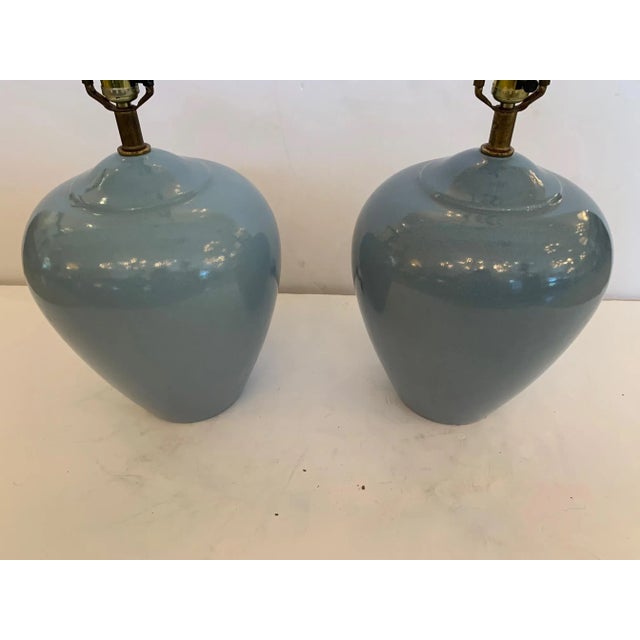 Lovely pair of Mid-Century Modern grayish blue pottery lamps with elegant urn shape and crazed surface. One lamp is a...