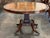 A Regency rosewood center table with a round tilt-top — bold rosewood grain framed by a wide band of brass scrollwork...