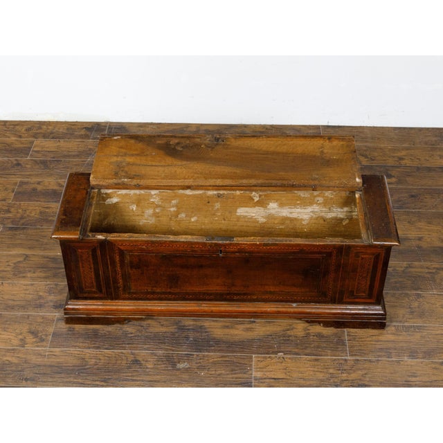 An Italian walnut coffer from the 18th century with lift top, geometric marquetry décor and bracket feet. This exquisite...