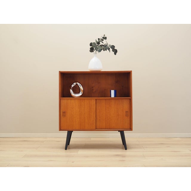 The bookcase was made in the 1970s, Danish production. The structure is covered with teak veneer. The legs are made of...