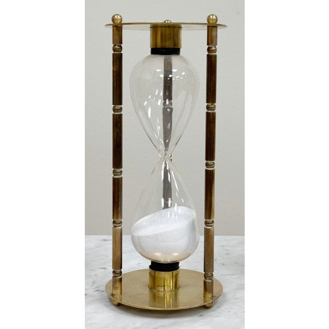 Vintage brass hourglass sand timer with white sand. Features a three pillar bamboo ribbed brass frame connecting two...