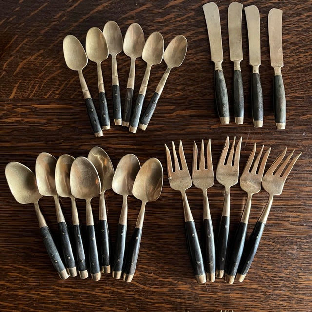 mid-century modern flatware set featuring black riveted handles with warm brass-tone stainless steel. A timeless...