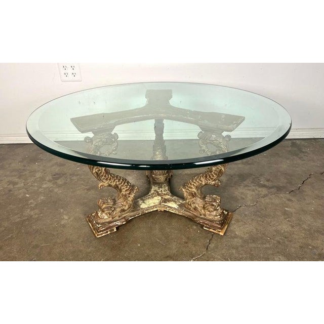 This is a unique coffee table featuring a round glass top and an intricately carved gilt wood base. The base is made of...