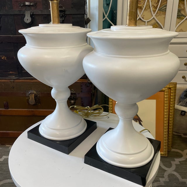 Pair of very stately and classic metal urn table lamps in a white satin finish with black metal base.These are being sold...