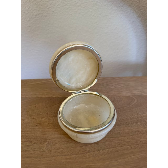 A small round box hand-carved from Italian alabaster, the lid set with a painted floral panel. Alabaster takes a carve and...