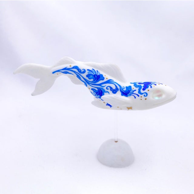This artwork features a delicately crafted fish, rendered in resin cast and adorned with intricate blue patterns that...