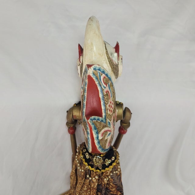 Handcrafted Indonesian Wayang Golek rod puppet featuring a detailed carved wooden head with blue eyes and a traditional...