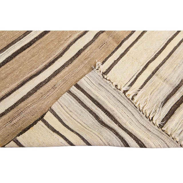 Beautiful vintage Turkish Kilim flatweave wool rug with a beige field. This piece has brown and tan accents in a gorgeous...