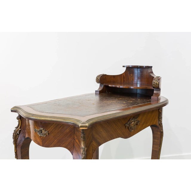 This small Baroque style desk was manufactured in the 19th century in France. It is made of walnut with leather and bronze...