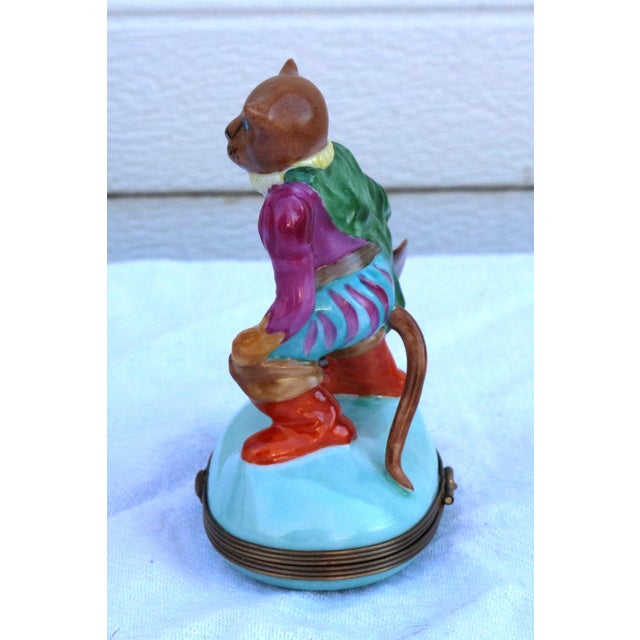 The Puss N' Boots Limoges Snuff Trinket Box is a charming 4" tall porcelain box featuring intricate hand-painted details...
