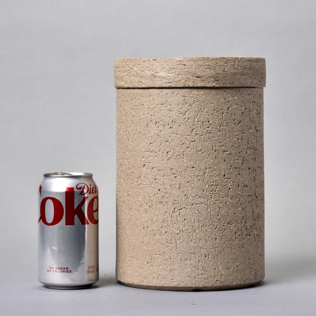Hand-thrown stoneware vessel with fitted lid in natural earth tones. The heavily textured surface showcases the organic...