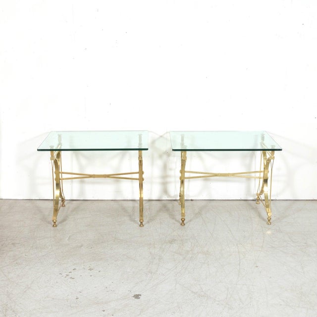 A striking pair of mid-20th century French gilt brass console tables with glass tops, attributed to the legendary Parisian...