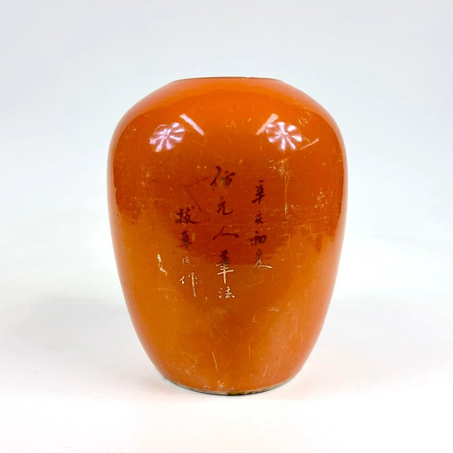 A beautiful orange vase with gold gilt illustration of a large crane on a pine tree. On the other side of the vase is...