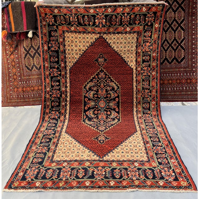 Persian Senneh design hand-knotted rug featuring a large rust diamond medallion filled with dense herati lattice and a...