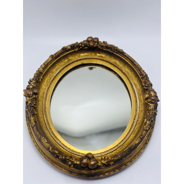 This elegant antique oval giltwood wall mirror exudes classic European charm with its richly ornamented frame and warm,...